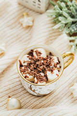 Hot Chocolate Marshmallow Coffee cup with Christmas decorations on knitted woolen plaid. Cozy home morning, relax concept.