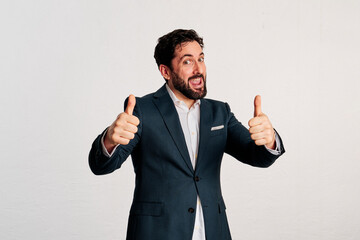 A excited adult man wearing a jacket and shirt showing thumbs up to camera in a white background - 466605171