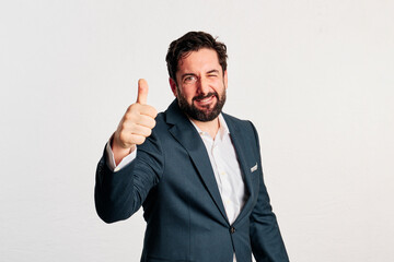 A excited adult man wearing a jacket and shirt showing thumbs up to camera in a white background - 466605181