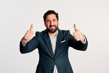 A excited adult man wearing a jacket and shirt showing thumbs up to camera in a white background - 466605190