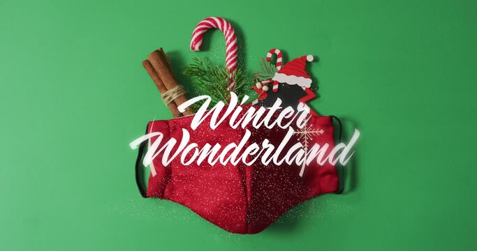 Animation of winter wonderland text over face mask and christmas decoration