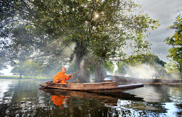 Unseen elderly monk boating pass ruins temple and Bodhi Tree to get food offering