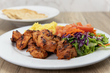 Tikka chicken grilled to perfection served with rice, salad, and pita flat bread for a hearty Mediterranean meal