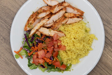 Overhead view of complete grilled tikka chicken meal sliced up with rice and salad for a hearty appetite