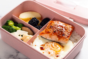 Kid school lunch bento box set of grilled salmon, egg, rice and vegetables