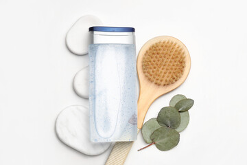 Bottle of shower gel, spa stones and massage brush on white background