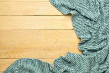 Crumpled knitted plaid on color wooden background