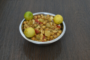 Indian home made chaat made of chickpea, tomatoes, potato, onion, lemon and other Indian masalas in steel bowl