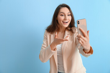 Fototapeta premium Happy woman taking selfie on color background