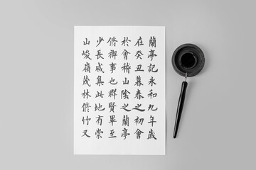 Tools for calligraphy and paper with Asian hieroglyphs on light background