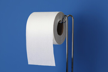 Modern holder with toilet paper roll on color background, closeup