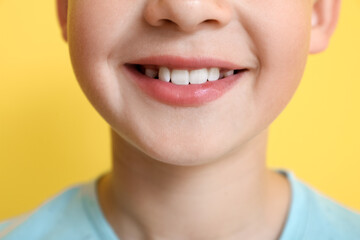 Little boy with healthy smile on yellow background, closeup