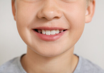 Little boy with healthy smile on light background, closeup