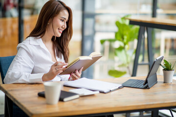 Shot of an Asian young businesswoman working on a laptop computer in her workstation.Portrait of Business people employee freelance online marketing e-commerce telemarketing concept.