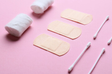 Bandage, medical plasters and cotton buds on color background, closeup