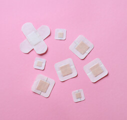 Different adhesive plasters on pink background