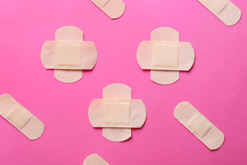 Different elastic medical plasters on pink background
