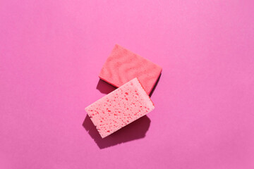 Pink cleaning sponges on color background