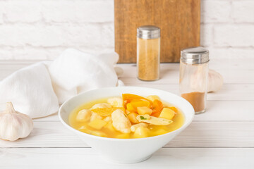 Bowl of tasty dumpling soup on light wooden table