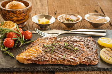 beef ribeye steak on stone plate with sauce and bread and butter