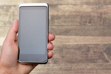 A hand holding a smartphone with a blank screen