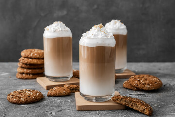 Glasses of tasty latte with nuts on grunge background