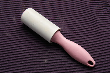 Lint roller and pet hair on purple textile background