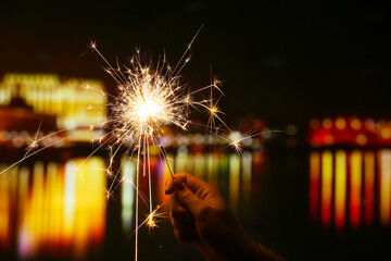 Female hand with beautiful sparkler at night outdoors