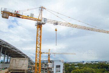 Construction site with yellow lifting crane and blue sky background.