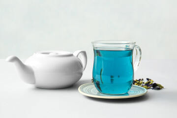 Teapot and glass cup of organic blue tea on white background