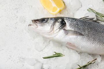 Fresh uncooked sea bass fish and lemon on light background, closeup