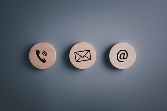 E-mail address ,telephone number and letter icons print screen on circle wooden block on table for webpage business contact and customer service concept..