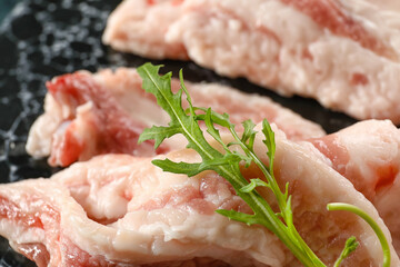 Board with slices of uncooked bacon on table, closeup