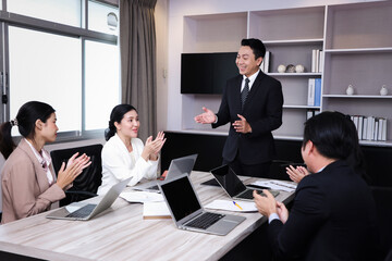 Group of business people applauding sitting at the negotiating table in meeting room. Selective focus