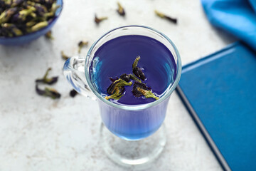 Glass of organic blue tea on light background