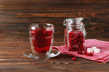 Glass of tasty lingonberry tea and berries on wooden background