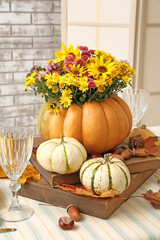 Beautiful bouquet of autumn flowers in pumpkin on served table