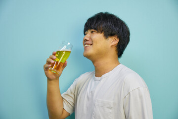 美味しそうにビールを飲む若いアジア人男性	
