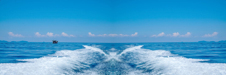 Fototapeta na wymiar Water splash behind the ship or wake of speed boat in the ocean with beautiful blue sky and white clouds use for holiday and transportation background