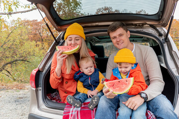 Young family had a picnic while sitting in the trunk of a car. Wellness concept.