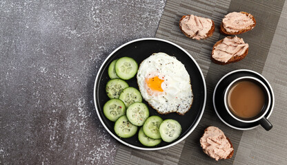 Sunny side up fried egg and sandwiches on a round plate on a dark background. Top view, flat lay