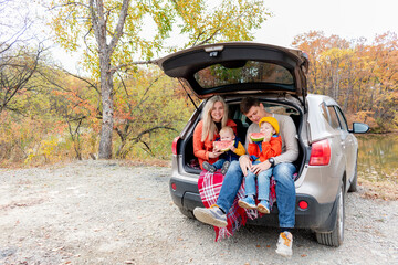 Young family had a picnic while sitting in the trunk of a car. Wellness concept.