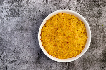 Mac and cheese, american style macaroni pasta with cheesy sauce and crunchy topping in a white baking dish on a dark grey background. Top view, flat lay