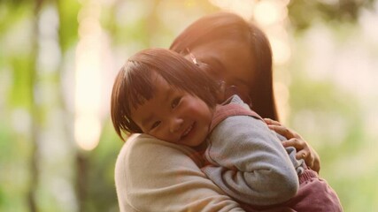 Slow motion asian mother holding her baby girl smile daughter holding Mom relax in the autumn park