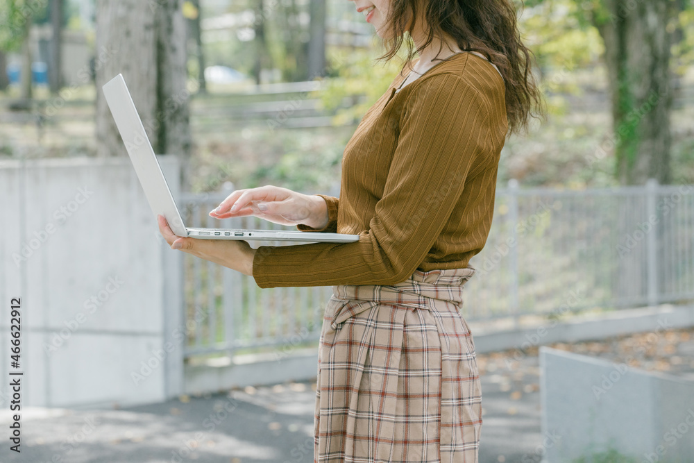 Poster 外でノートパソコンを開く女性　 ノートパソコンで調べ物をする女性