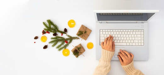 The girl's hands on the laptop keyboard. Christmas layout, with laptop and gifts and decorations.