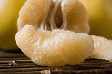 Ripe pomelo with pomelo slices on wood background