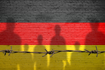 The refugees migrate to Germany . Silhouette of illegal immigrants . Europe union migration policy. Germany flag painted on a brick wall