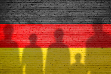 The refugees migrate to Germany . Silhouette of illegal immigrants . Europe union migration policy. Germany flag painted on a brick wall