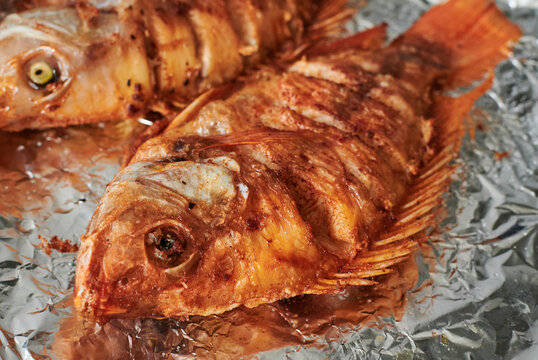 A Couple Of Fried Fish Lying Ready To Eat Very Golden Brown A Little Burned On An Aluminum Grill In A Balca Kitchen